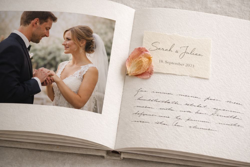 Persönliche Details wie Einladungskarten und getrocknete Blumen in einem Hochzeitsalbum