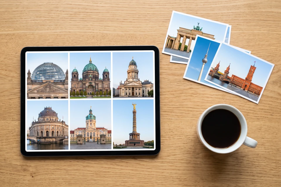 Tablet mit Berlin-Fotos und ein Stapel Fotoabzüge auf einem Schreibtisch