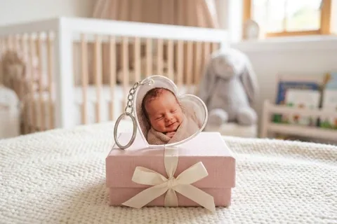 Schlüsselanhänger in Herzform mit Babyfoto auf einer Geschenkbox