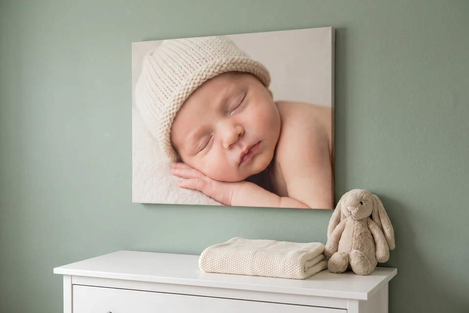 Leinwand mit Foto eines schlafenden Neugeborenen über einer Kommode im Kinderzimmer