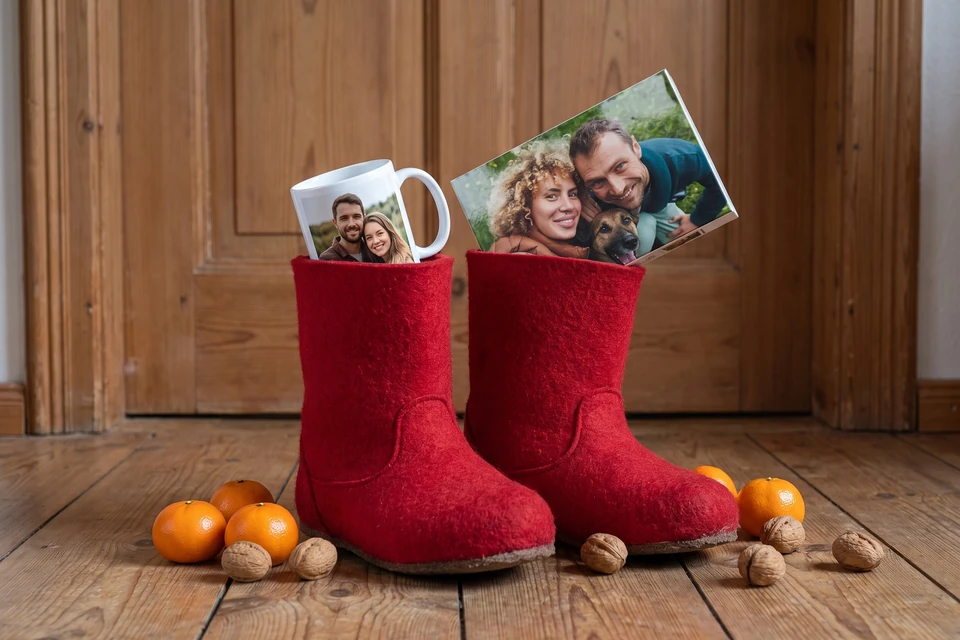 Nikolausstiefel mit Fotogeschenken auf einem Holzboden