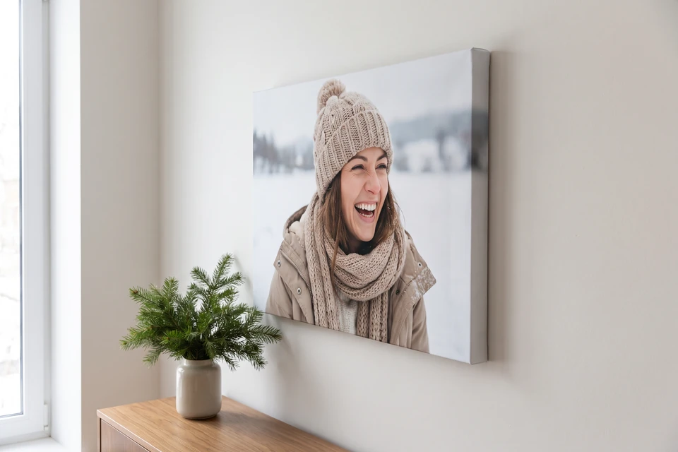 Leinwand mit Porträt einer lachenden Frau im Schnee an einer hellen Wand
