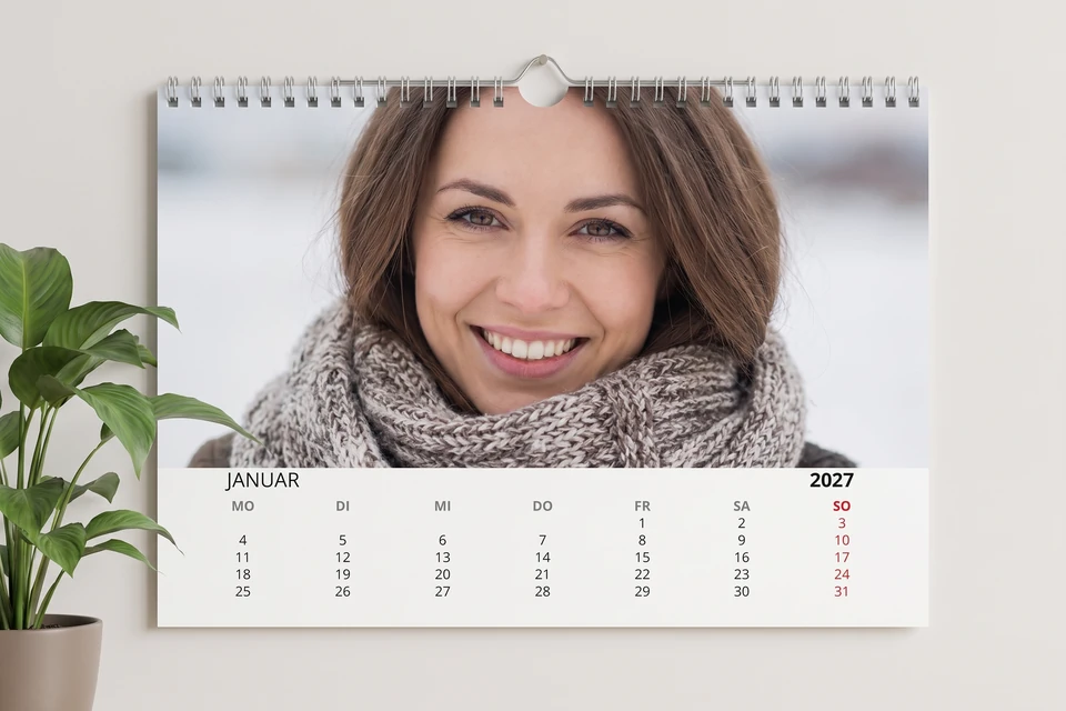 Wandkalender mit Winterfoto einer Frau an einer hellen Wand