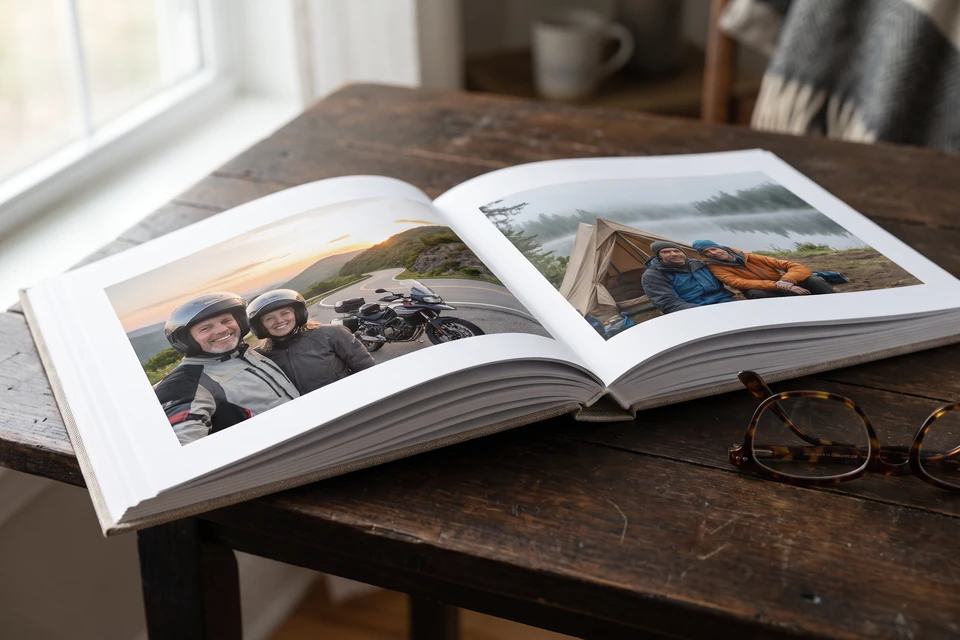 Aufgeschlagenes Fotobuch mit Motorrad- und Bergfotos