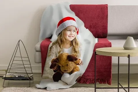 Kind mit Fotodecke auf dem Sofa an Weihnachten
