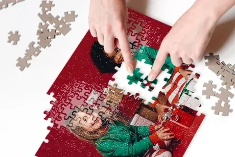Hände legen ein Fotopuzzle mit Familienmotiv zusammen