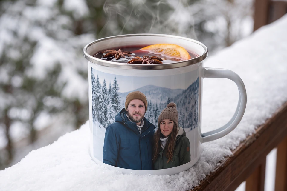 Emaille-Tasse mit Glühwein auf einem verschneiten Balkon